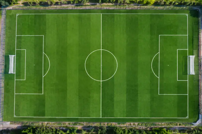Kale çizgileri, ceza sahaları ve orta çizgisi görünen futbol sahasının üstten görünümü